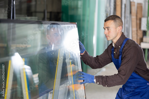 Fotografía Experienced male glazier controlling quality of sheet glass in workroom
