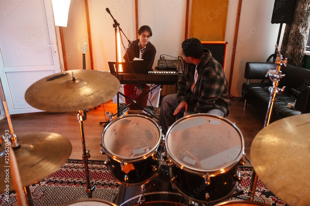 Fototapeta premium Two young musicians playing keyboard in a creative music studio