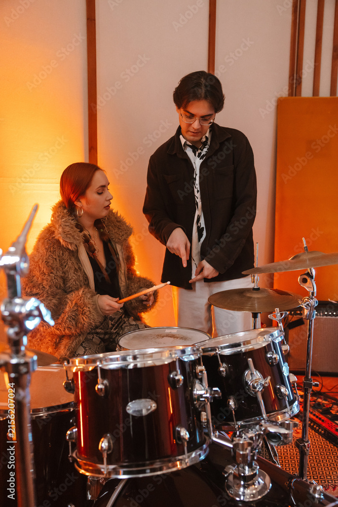 Fototapeta premium Two young musicians teaching drumming in a creative music studio