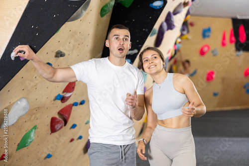 Fotografie Two novice climbers, young girl and man, standing in training room by colorful a