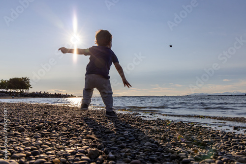 Child Skipping Stones on Crescent Beach at Sunset — Playful Toddler Throwing Pebbles on Shore