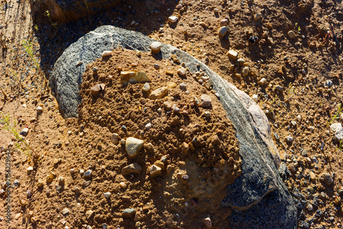 Obraz na plátne Large textured granite gneiss boulder covered with sand and small stones inside