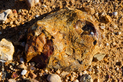 Foto Raw brown flint nodule with sharp conchoidal percussion scars lying on sandy des