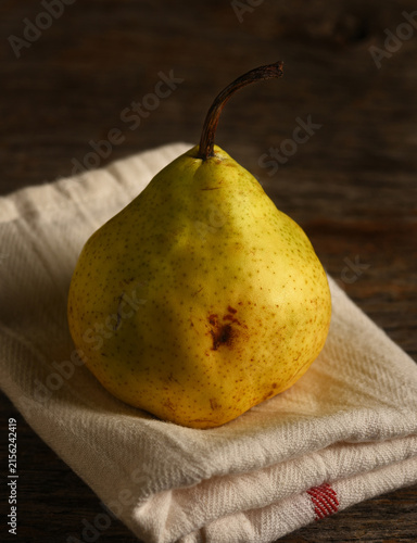 Pear Still Life. An Anjou Pear on a folded kitchen towel on a rustic wooden table.