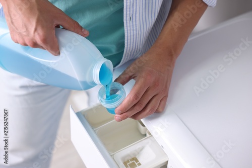 Canvastavla Man pouring liquid laundry detergent from bottle into cap near washing machine,