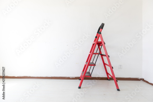 A red ladder in an empty room