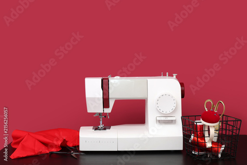 Obraz na płótnie Modern sewing machine with tailors supplies on red background