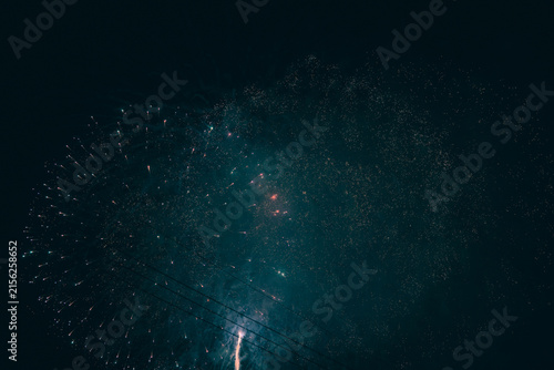 Bild auf Leinwand Fading firework sparks dissolving into a vast dark teal sky