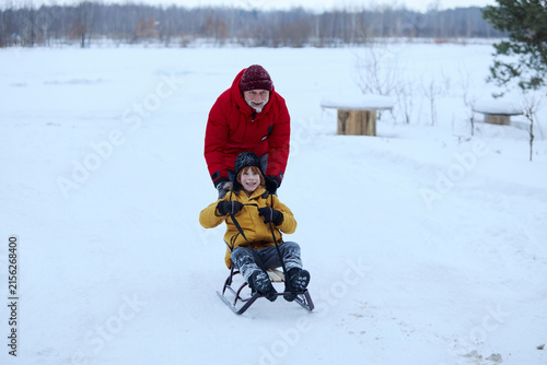 Fotografie Grandfather and grandson sled riding during a winter outdoor adventure