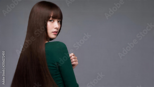 緑の長袖で振り向き超ロングストレートヘアを見せる前髪の日本人女性