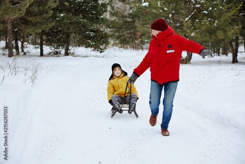 Canvas Print Grandfather and grandson pulling sledge during a winter outdoor adventure