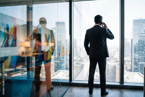 Corporate executive talking on mobile phone looking out city window