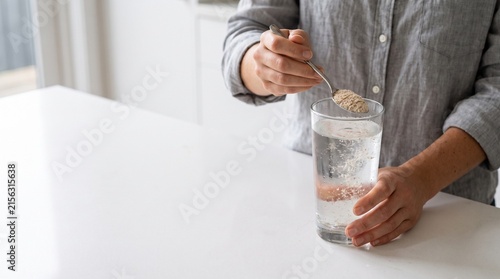 Person stirring supplement powder into a glass of water
