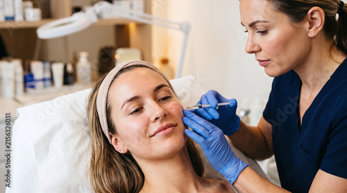 Female doctor administering mesotherapy micro injections on patient cheek.