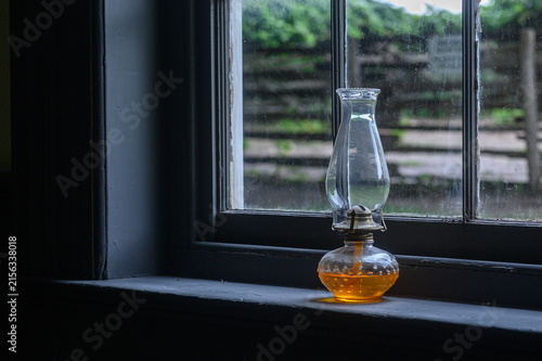 Antique oil lamp sitting on a rustic window sill