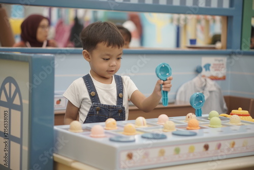 Cute Asian toddler boy holding blue toy scoop in pretend play