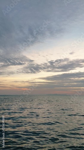 Tranquil sea waves under twilight sky during sunset with soft glowing horizon and calm atmosphere, vertical orientation.