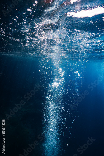 фотографія Bubbles rising to the water surface in blue ocean with sunlight.
