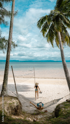 Top view of couple tourist are in motion of relaxing stay under coconut palm tree at the the edge of the sea beach,  trip summer on vacation of couple lover