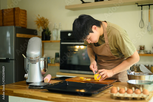 Canvastavla Man in Apron Slicing Lemon on Cutting Board in Modern Home Kitchen While Baking
