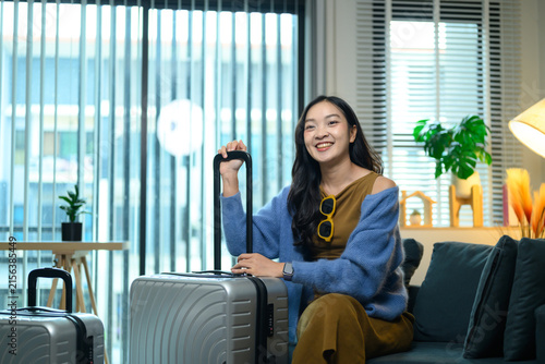 Happy Young Woman Ready to Travel Sitting with Luggage Suitcase at Home Living Room