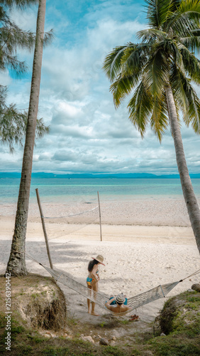 Top view of couple tourist are in motion of relaxing stay under coconut palm tree at the the edge of the sea beach,  trip summer on vacation of couple lover