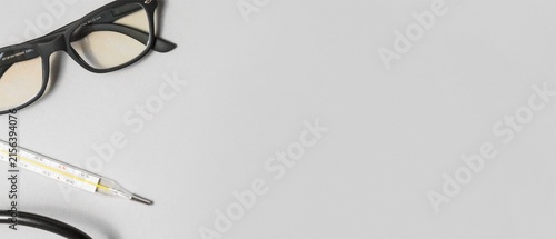 Glasses, Thermometer and Stethoscope on Gray Background with Copy Space