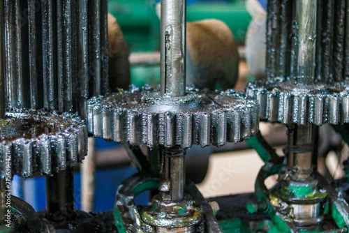 Heavy industrial metal gears covered in thick black grease, Close up shot of mechanical machine cogwheels, Factory machinery parts background