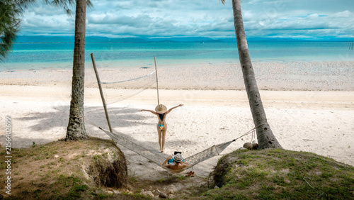 Top view of couple tourist are in motion of relaxing stay under coconut palm tree at the the edge of the sea beach,  trip summer on vacation of couple lover