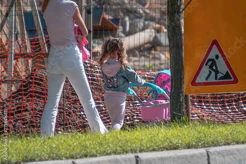 Mother and daughter walk to a construction site on a summer day