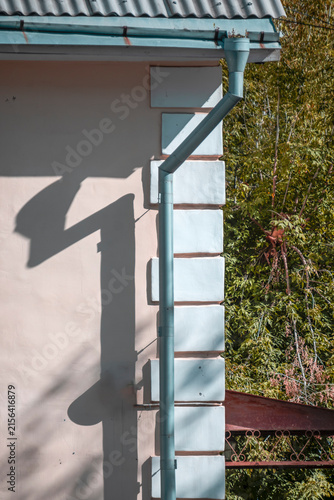 An old downpipe on the wall of a building on a summer day