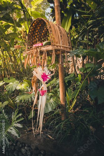 Balinese traditional offerings and ritual decorations crafted from bamboo and palm leaves. Placed in a natural Hindu shrine within a tropical jungle in Bali. Indonesia