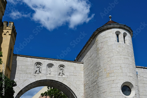 closeup of stone city gate and bastion. Veszprem, Hungary. recently renovated structure. stone sculptures in wall alcoves. sloped clay roof. round window. low angle view. architecture, travel concept