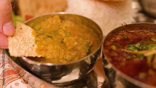Hand Dipping Papadum into Indian Dal Lentil Stew Thali