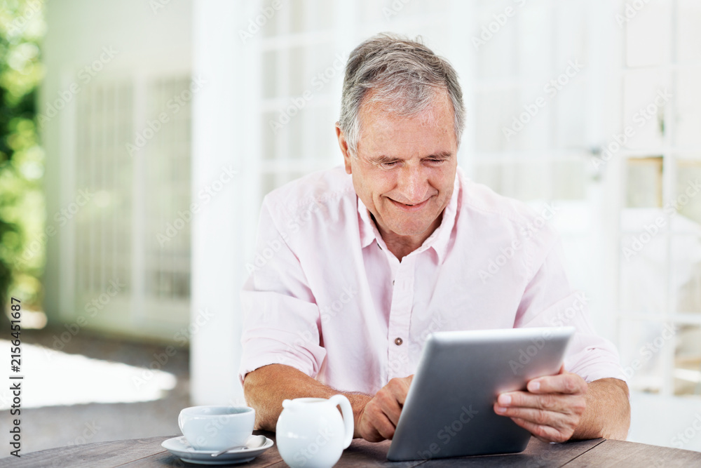 Fototapeta premium Reading, coffee and tablet with old man in home for retirement fund savings, pensioner asset and budget. Tax return, drink and loan approval with senior person in apartment for online finance