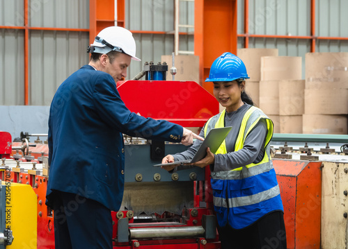 Corporate manager industrial engineer holding laptop discussing operational safety machinery control inside modern manufacturing plant  leadership smart factory technology corporate partnership.