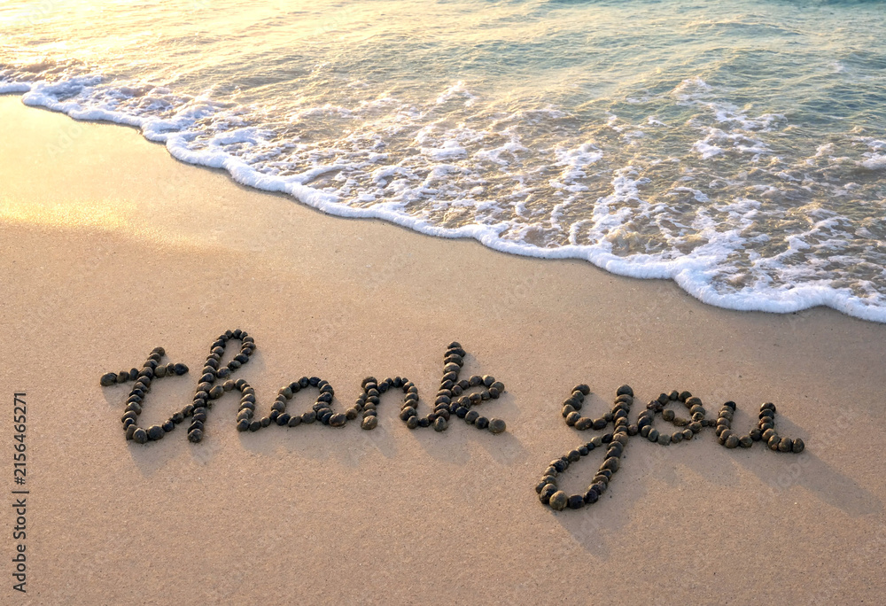 Fototapeta premium Heartfelt thank you message beautifully written in pebbles on sandy beach near ocean waves
