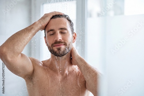 Handsome man with beard enjoying a refreshing shower in a bright modern bathroom