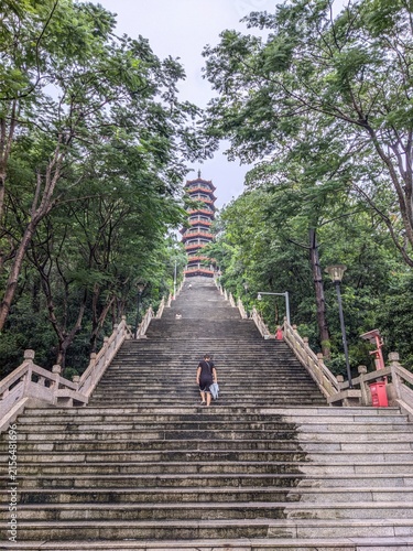 Photography Person climbing stone stairs towards tall pagoda