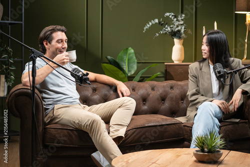 Fotografie Two people sitting on a sofa, conversing into microphones during a broadcast