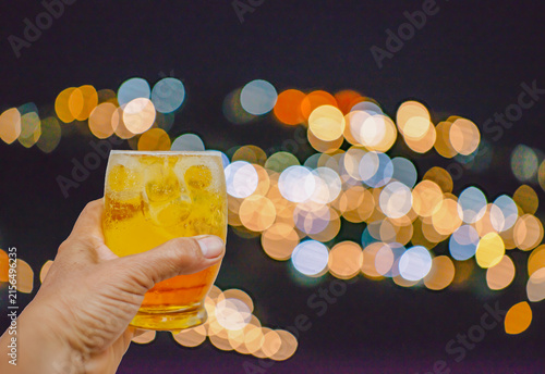 Holding a beer glass against a beautiful bokeh background.