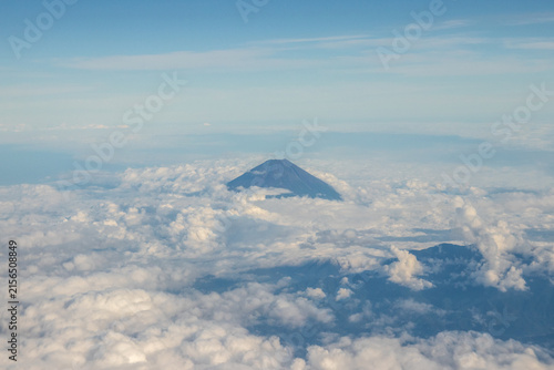 Fotografie Mount Fuji peeking above a sea of clouds seen from an airplane