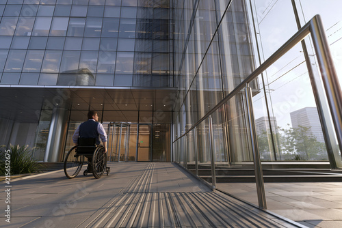 Man in wheelchair entering a modern office building ramp