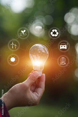 Hand holding glowing lightbulb with green energy and environmental protection icons