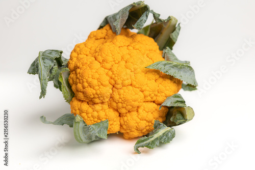 Fresh orange cauliflower head with green leaves isolated on white background