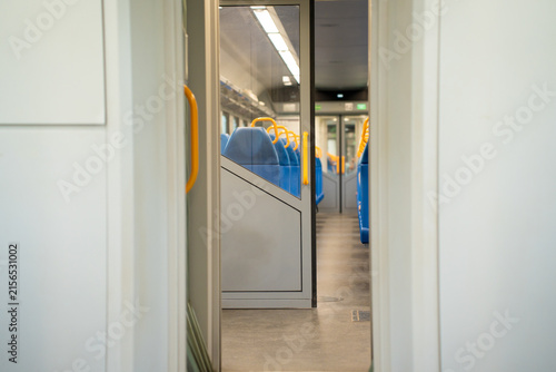 Fotografía Sliding door in a commuter train car with empty blue seats