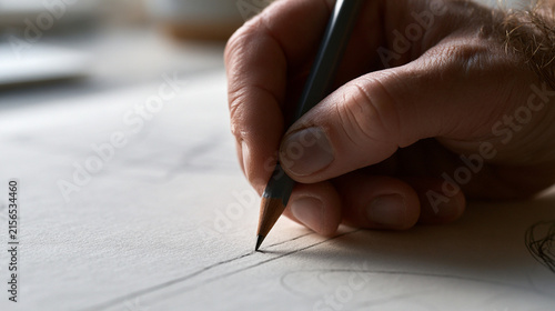 Closeup of a persons hand drawing with a pencil on paper