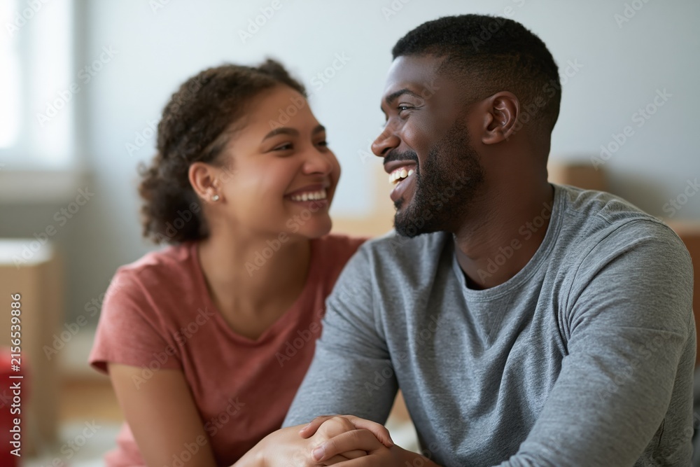 Fototapeta premium Happy multiracial couple sharing a joyful moment, looking at each other with smiles and affection