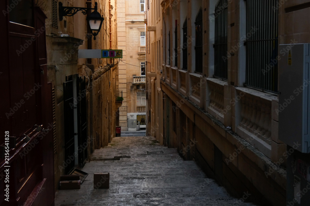 Fototapeta premium Narrow street with parked cars leading to the sea in valletta, malta