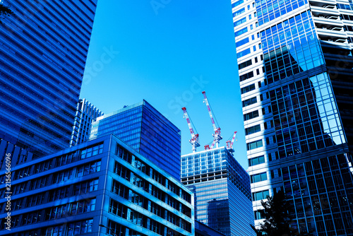 Modern skyscrapers and construction tower cranes building new office architecture in Tokyo business district under blue sky.